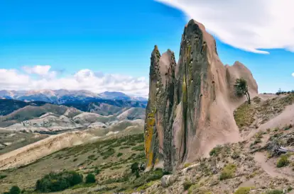 paisaje de la estepa con tonos azules y verdes sobre los pliegues de los cerros. también se ven las rocas con formas extrañas adelante.