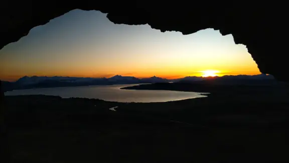 Atardecer hacia el lago y los cerros bien al fondo mirando desde dentro de la cueva del cerro Villegas.