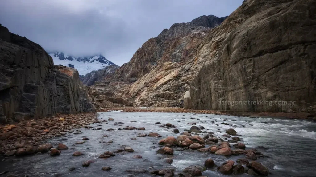 río encajonado con un cerro y glaciares al fondo